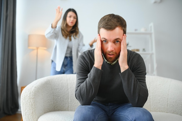 Une dispute familiale un homme et une femme assis sur le canapé à la maison une femme en colère hurle à son mari