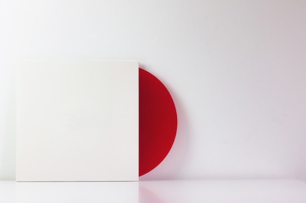 Photo disque vinyle rouge, dans sa boîte blanche, avec un espace vide pour écrire.