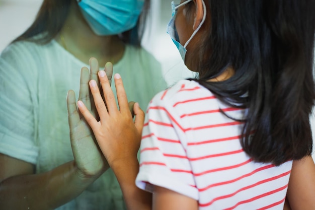 Photo la distanciation sociale au sein de la famille en gros plan sur les mains d'une mère et d'une fille sur un avion de fenêtre