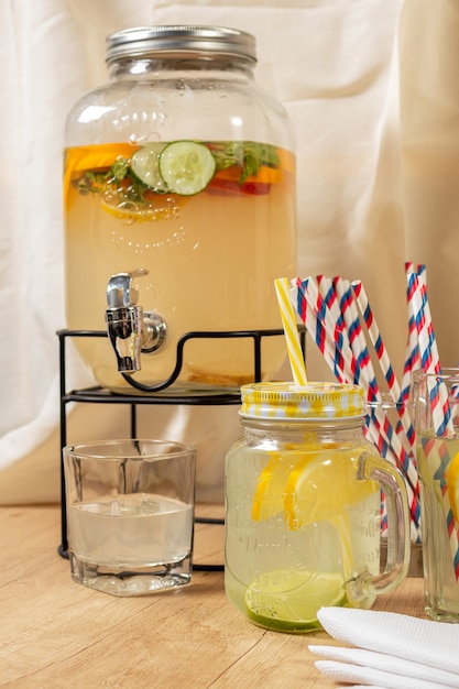 Distributeur de boissons naturelles avec du jus d'agrumes maison sur une surface en bois, différents types de verres et cruches avec sorbet et glace