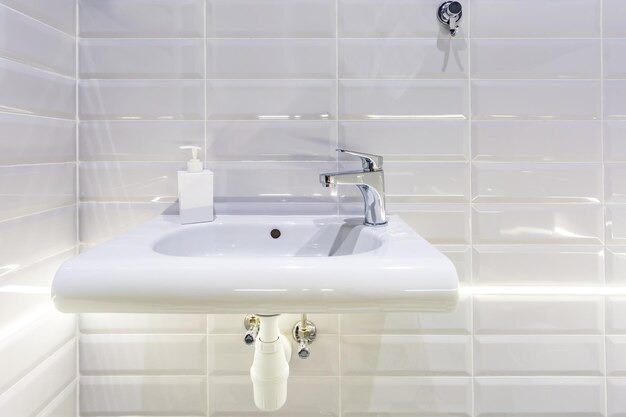 Distributeurs de savon et de shampoing près d'un lavabo en céramique avec robinet dans une salle de bains loft chère