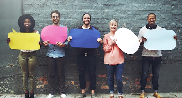 Dites-le comme vous l'entendez Photo d'un groupe diversifié de personnes brandissant des bulles contre un mur de briques grises