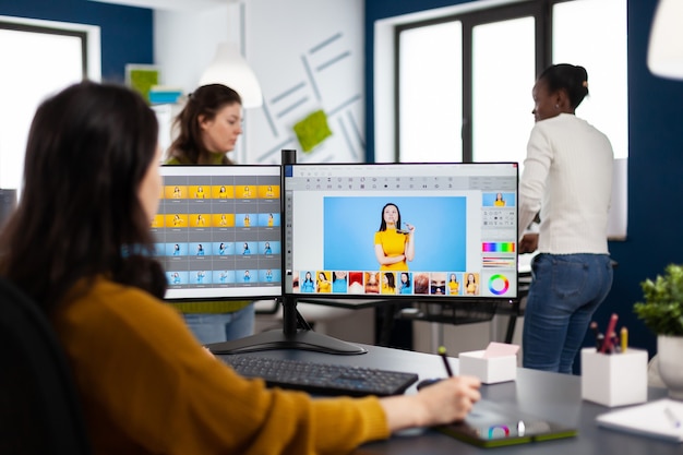 Éditeur graphique photo retouchant des photos du client dans une application professionnelle avec un stylet travaillant dans un studio de création de démarrage