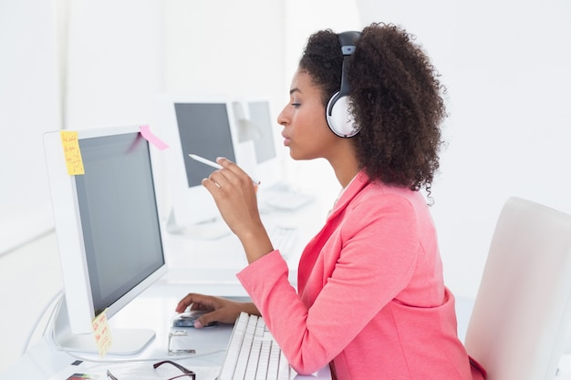 Éditeur de photo occasionnel travaillant au bureau en écoutant de la musique