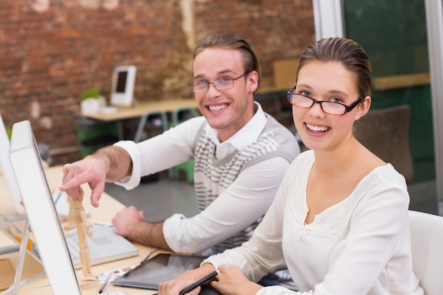 Éditeurs de photo souriant à l&#39;aide d&#39;ordinateur dans le bureau