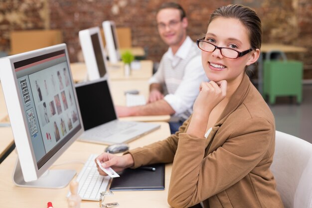 Éditeurs de photo souriant à l&#39;aide d&#39;ordinateurs dans le bureau