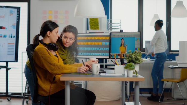 Éditeurs de photos de femmes confiantes assis sur leur lieu de travail dans un studio de création, directeur artistique de retouche photo ...