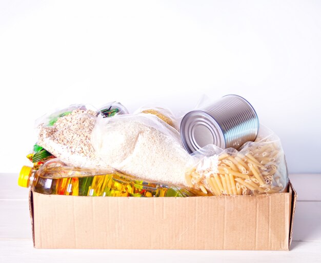 Divers aliments en conserve et céréales dans une boîte en carton. Dons de nourriture. Livraison de nourriture.