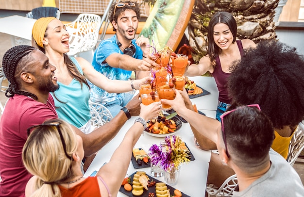 Divers amis qui traînent pour griller et boire des cocktails en plein air