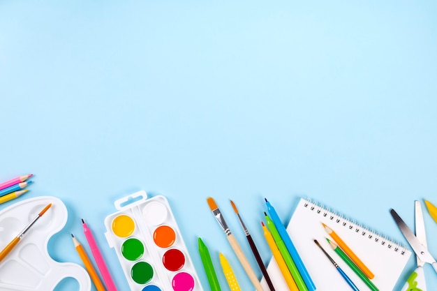 Divers bureaux de l'école et fournitures de peinture sur fond bleu. Retour au concept de l'école.