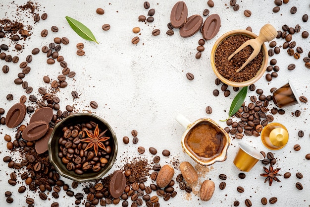 Divers café, grains de café torréfiés foncés, moulus et capsules avec cuillères sur béton blanc