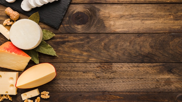 Divers délicieux fromage avec des feuilles de laurier et de noix sur bois texturé