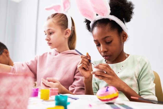 Divers enfants peignant des oeufs de Pâques