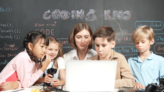 Divers étudiants écrivent du code d'ingénierie pendant que le garçon répare le tableau d'érudition