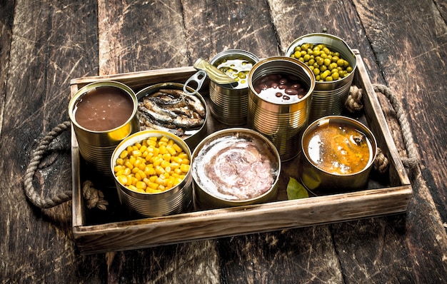 Divers fruits, légumes, poisson et viande en conserve dans des boîtes de conserve sur l'ancien plateau.