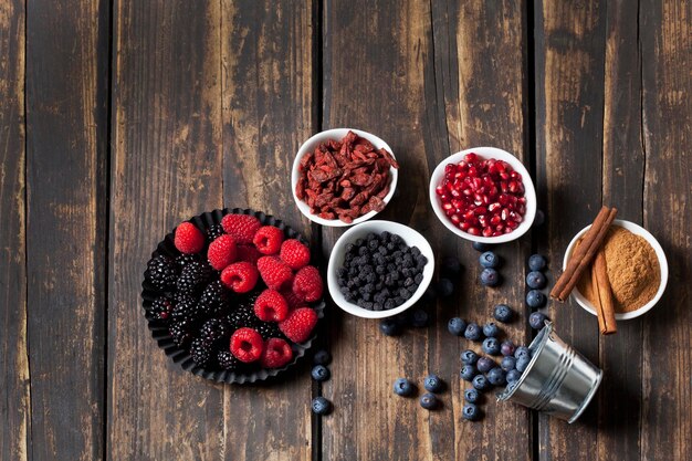 Divers fruits secs et frais et bol de cannelle en poudre avec des bâtons de cannelle sur bois