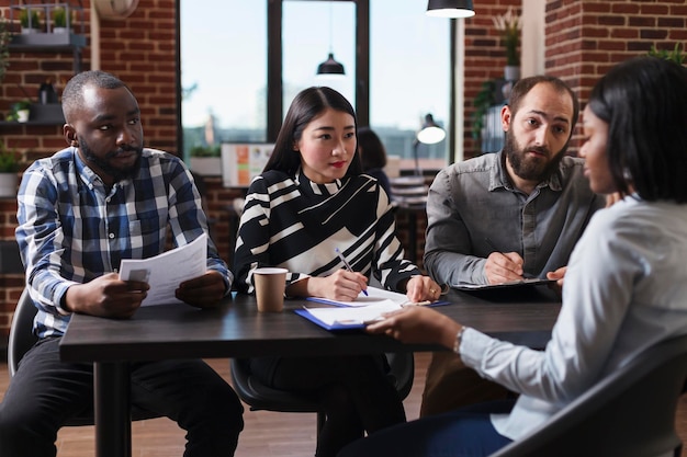 Divers hommes d'affaires interviewant un candidat afro-américain discutant d'un curriculum vitae recrutant un employeur pour un emploi dans les ressources humaines dans le bureau d'une entreprise en démarrage. Concept de processus d'embauche