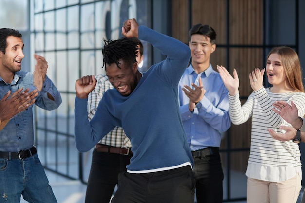 Divers hommes d'affaires ravis triomphent s'amusent à danser dans un couloir de bureau moderne