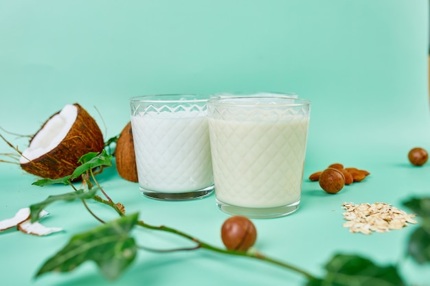 Divers lait et ingrédients végétaliens à base de plantes, lait non laitier, types alternatifs de lait végétalien dans des verres sur fond bleu avec espace de copie