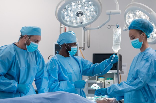 Photo divers médecins, hommes et femmes, portant des masques et des combinaisons chirurgicales en salle d'opération