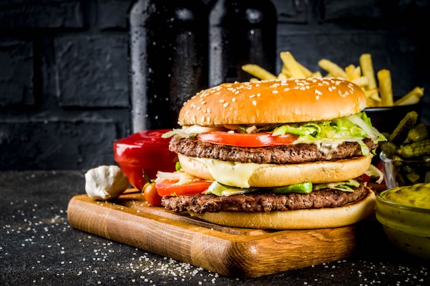 Divers plats de fête, hamburgers, frites, croustilles, concombres marinés, oignons, tomates et bouteilles de bière froide