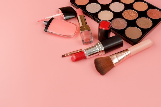 Divers produits de maquillage sur fond rose avec fond