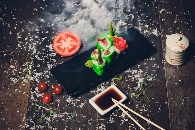 Divers sushis sur plaque blanche avec des baguettes sur fond en bois.