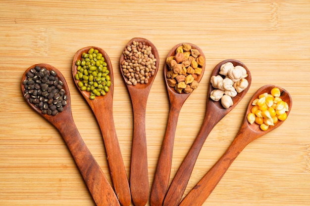 Divers types séchés de haricots et de pois dans une cuillère en bois.