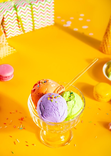 Diverses boules de crème glacée colorées ou plat de sundae de boules avec des macarons de cônes de gaufre sur fond jaune