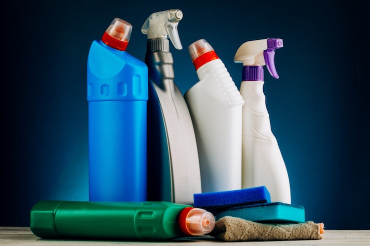 Photo diverses bouteilles de produits de nettoyage sur fond bleu.