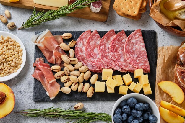 Diverses collations gastronomiques au vin. Bleuets, pêches, salami, prosciutto, pistache, pignons de pin, fromages variés, camembert et fines herbes. Snacks italiens pour des vacances importantes.