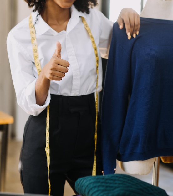 Diverses créatrices de mode féminines au travail avec des centimètres sur mesure sur le cou et tiennent une entreprise de conception créative indépendante pour tablette et smartphone en studio