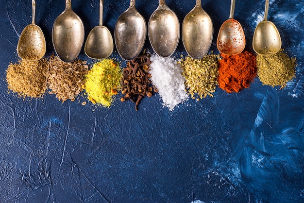 Diverses épices moulues curcuma poivre gingembre cannelle herbe assaisonnement paprika sel graines de carvi cuillère vintage sur la table. Vue d'en-haut. épices indiennes