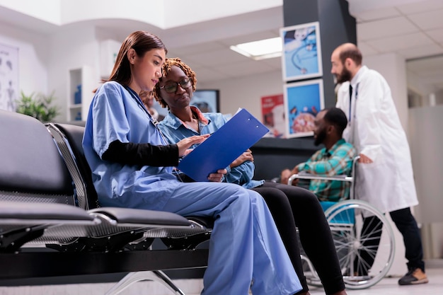 Diverses femmes parlent de services de santé à la clinique, discutent de traitement et de médicaments dans la salle d'attente. Assistante consultant une patiente lors d'un rendez-vous de contrôle.