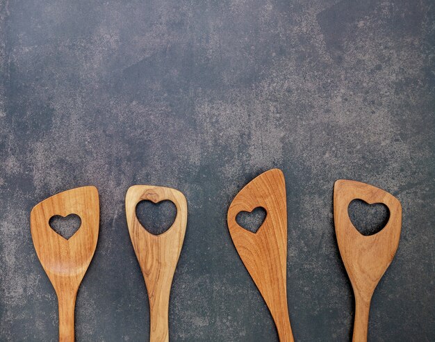 Diverses formes de coeur d'ustensiles de cuisine en bois sur fond de béton foncé avec espace plat et copie