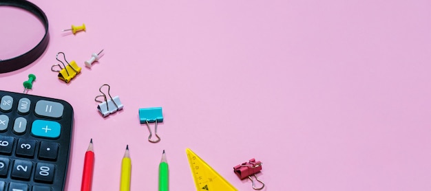 Diverses fournitures de bureau sur fond rose calculatrice et loupe de concept de retour à l'école avec pe...