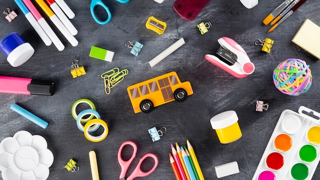 Diverses fournitures de bureau et de peinture sur fond noir. Retour au concept de l'école. Vue de dessus