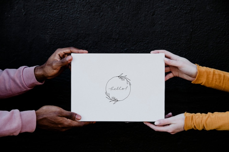 Photo diverses mains tenant une carte de maquette avec le texte "bonjour" sur fond noir