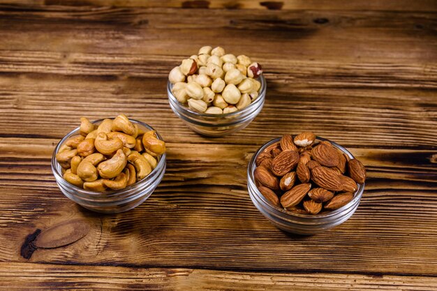 Diverses noisettes de noix de cajou amande noix dans des bols en verre sur une table en bois repas végétarien concept de saine alimentation