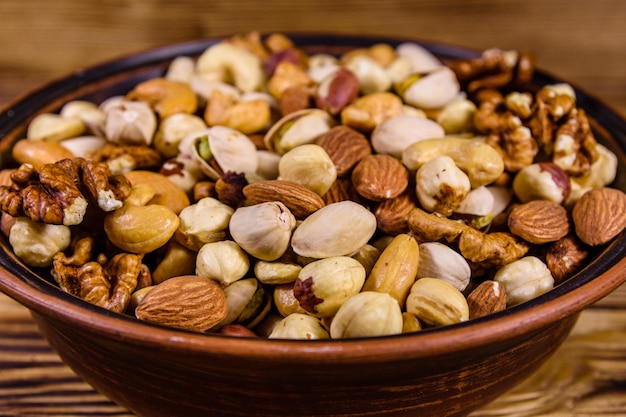 Diverses noix noix de cajou amande noisette pistache noix dans une assiette en céramique sur une table en bois repas végétarien concept de saine alimentation