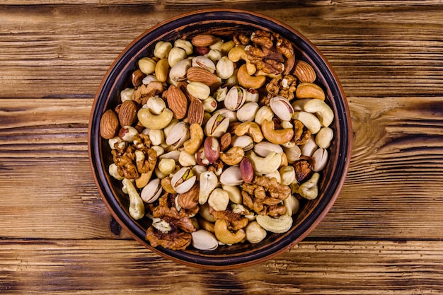 Diverses noix noix de cajou amande noix de cajou noisette pistache dans une assiette en céramique sur une table en bois Repas végétarien Concept de saine alimentation Vue de dessus