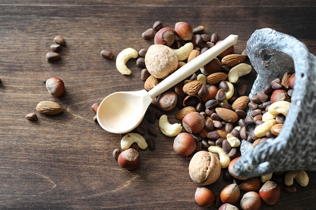 Diverses noix utiles et savoureuses sur une table en bois et des pots avec de l'herbe verte