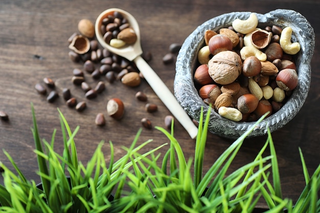 Diverses noix utiles et savoureuses sur une table en bois et des pots avec de l'herbe verte