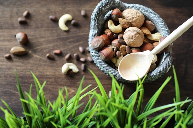 Diverses noix utiles et savoureuses sur une table en bois et des pots avec de l'herbe verte