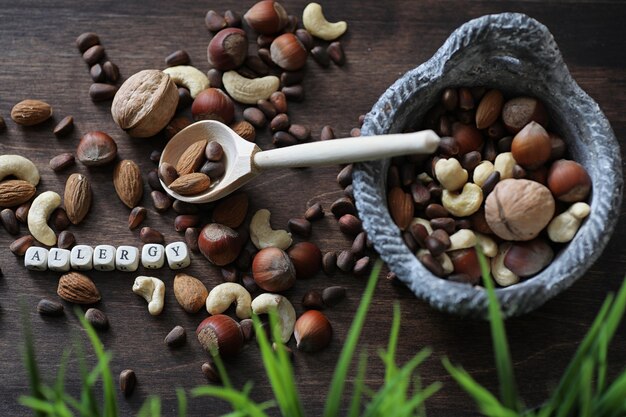 Diverses noix utiles et savoureuses sur une table en bois et des pots avec de l'herbe verte