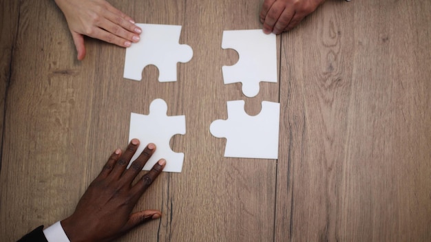 Diverses personnes de l'équipe assemblant un groupe multiracial de puzzle de collègues noirs et blancs