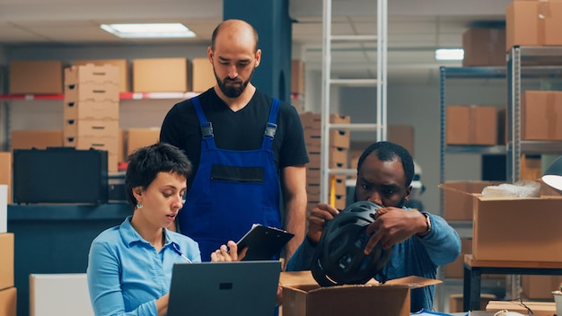 Diverses personnes expédient des produits à partir du stock de l'entrepôt et emballent des marchandises dans des boîtes. Entrepreneurs travaillant sur le développement de petites entreprises et l'expédition de marchandises, démarrage. Prise de vue à main levée.