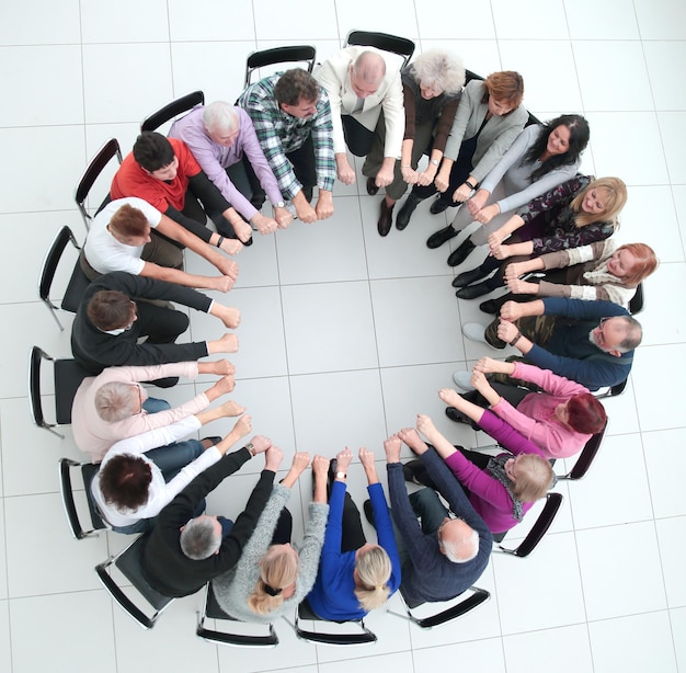 Diverses personnes matures assises en cercle et montrant leur photo d'unité avec un fond