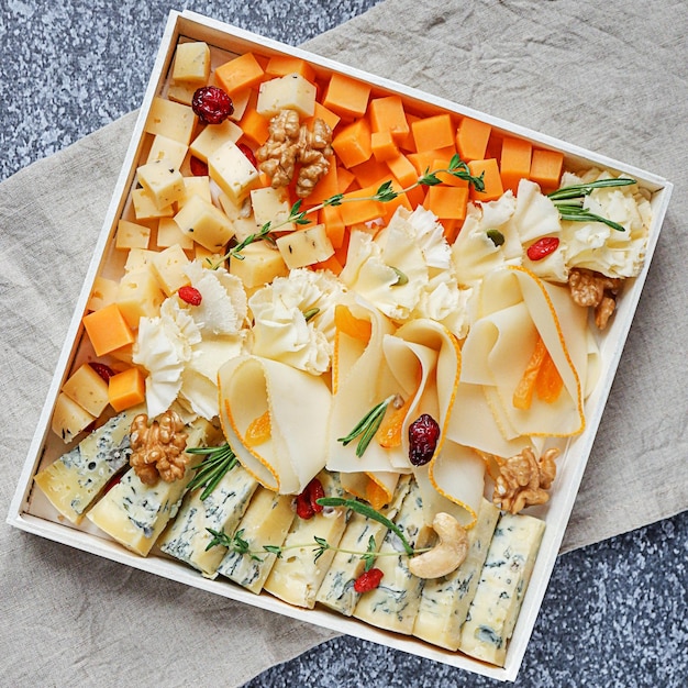 Photo diverses sortes de fromage disposées sur une assiette en bois, décorées de baies, de noix, d'herbes, vue de dessus