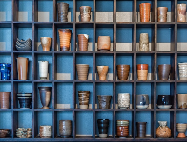 Diverses tasses en céramique sur une étagère en bois